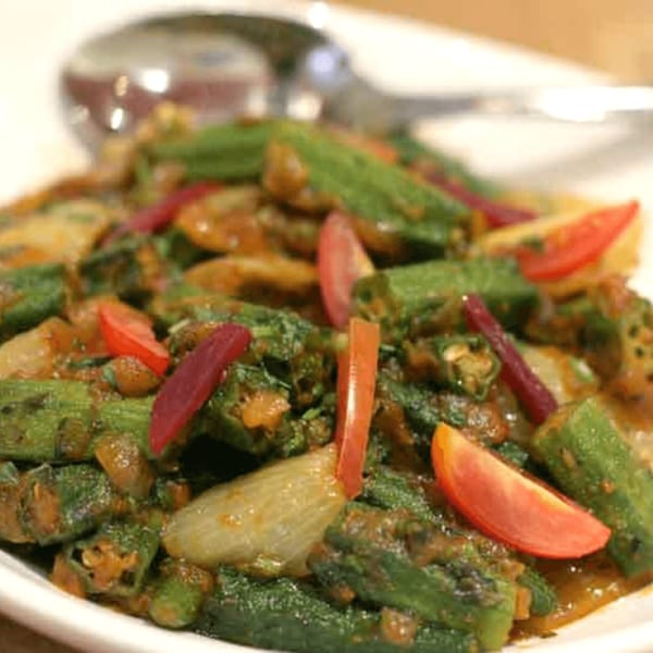 Close-up of Bhindi Masala, an Indian dish with okra, onions, and tomatoes in a rich sauce.