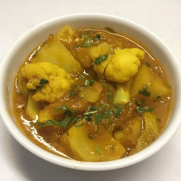 Aloo Gobi, an Indian dish with potatoes and cauliflower in a rich, orange curry sauce.